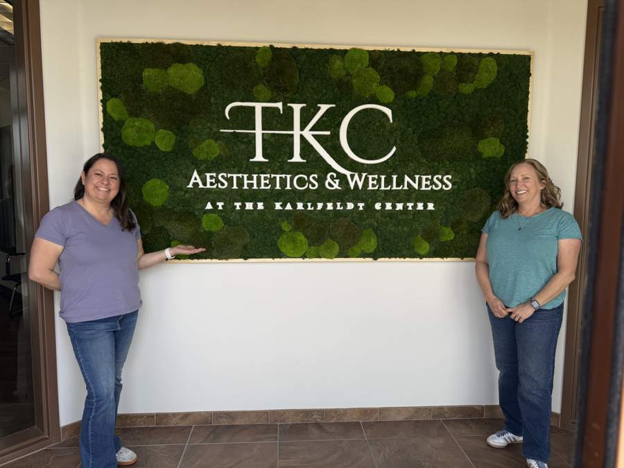 Two people beside the TKC moss wall, showing its scale