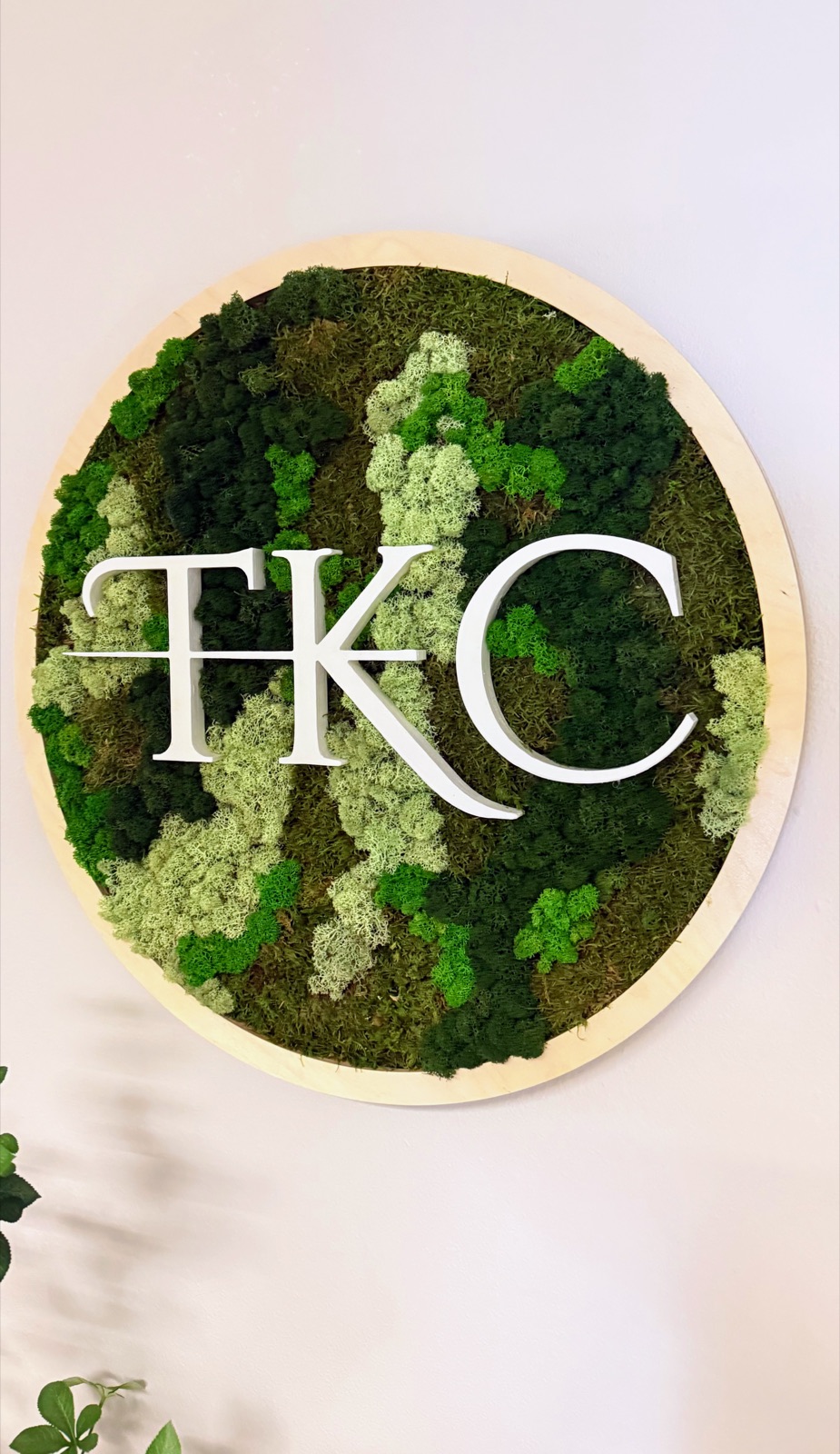 A round moss piece with the TKC monogram