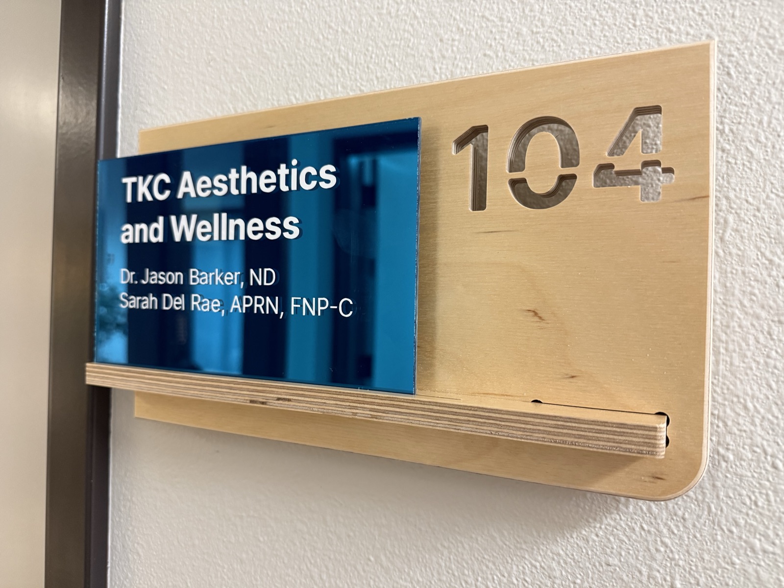 A birch suite-door sign for TKC Aesthetics & Wellness