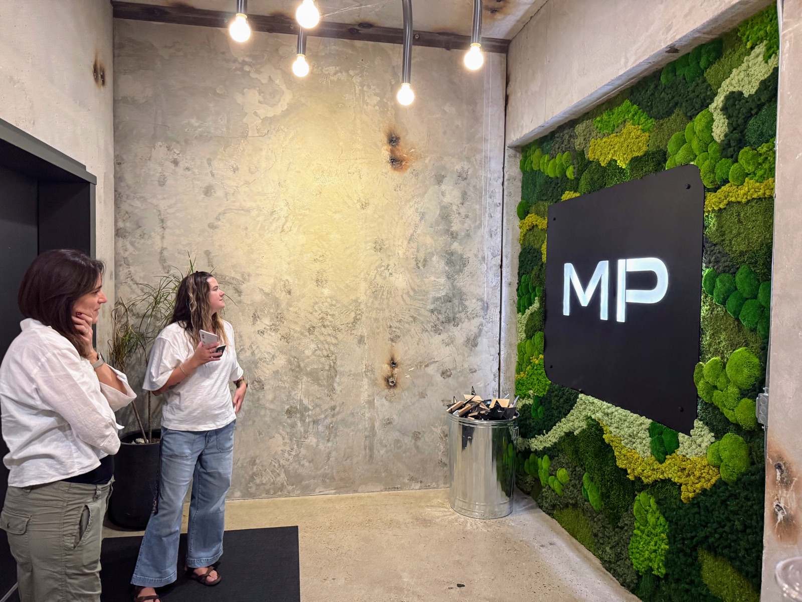 Visitors beside the Mitchell + Palmer moss wall, showing its scale